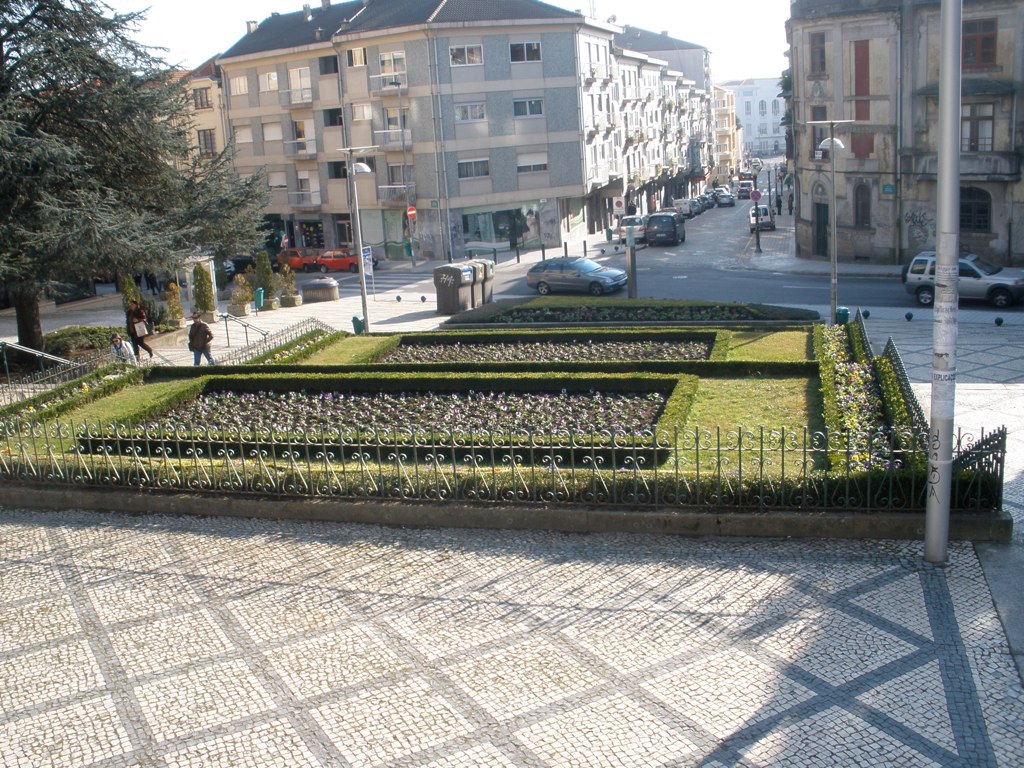 some people on a street and a boxwood garden