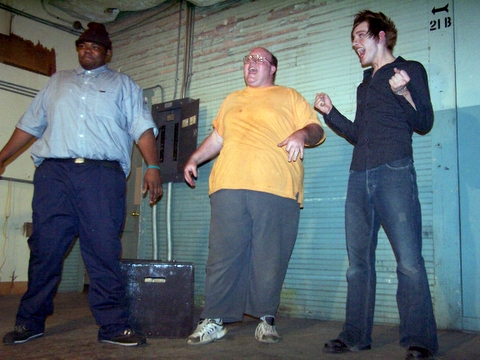 a group of men are standing outside and holding game controllers