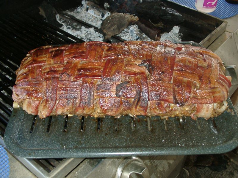 a barbecue with bacon cooking on a grill
