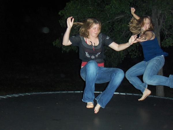 two girls jumping up and down on a trampoline