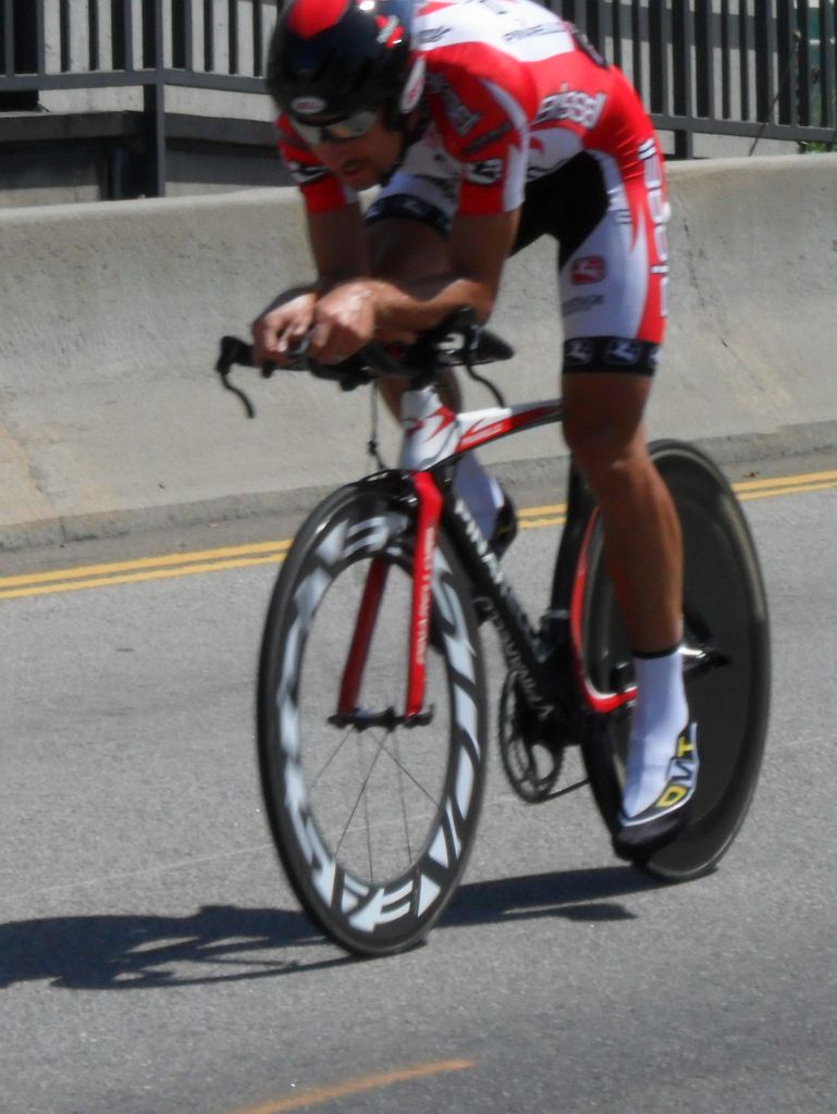 a bicyclist speeds along a road with a red and white jersey