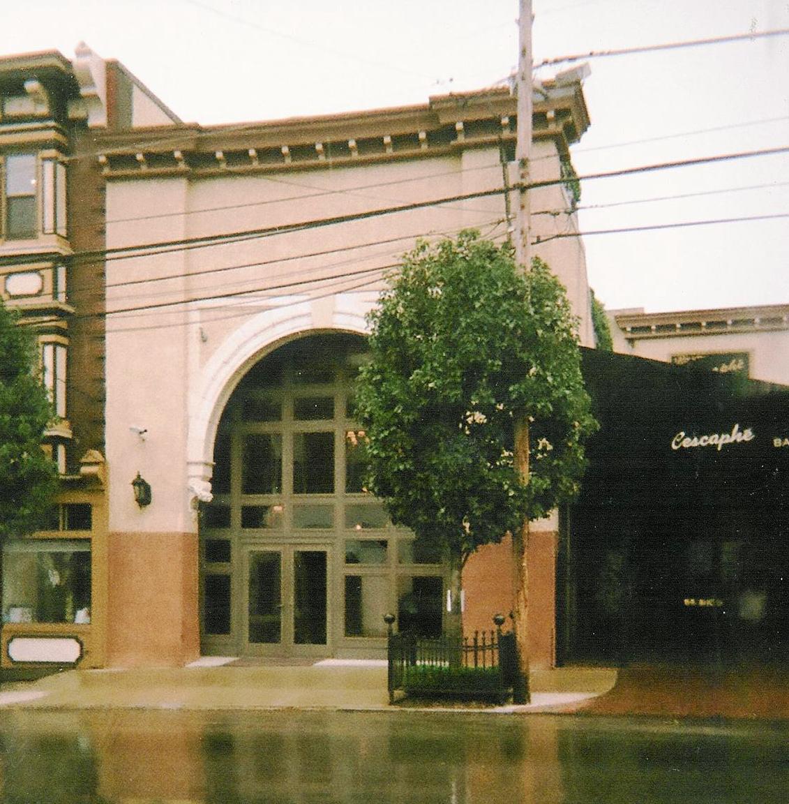 a wet sidewalk next to a tall brown building