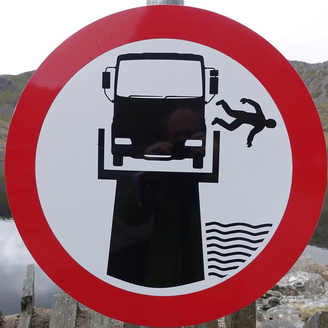 a sign depicting an upside down vandalized over a body of water