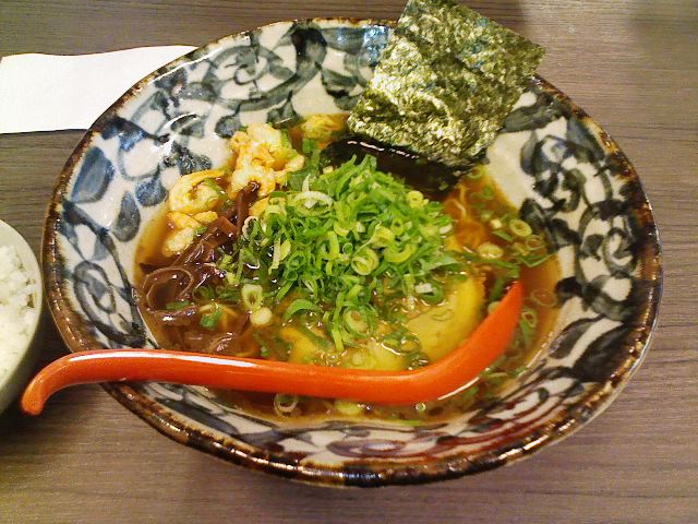 a bowl of food on a wooden table with broth