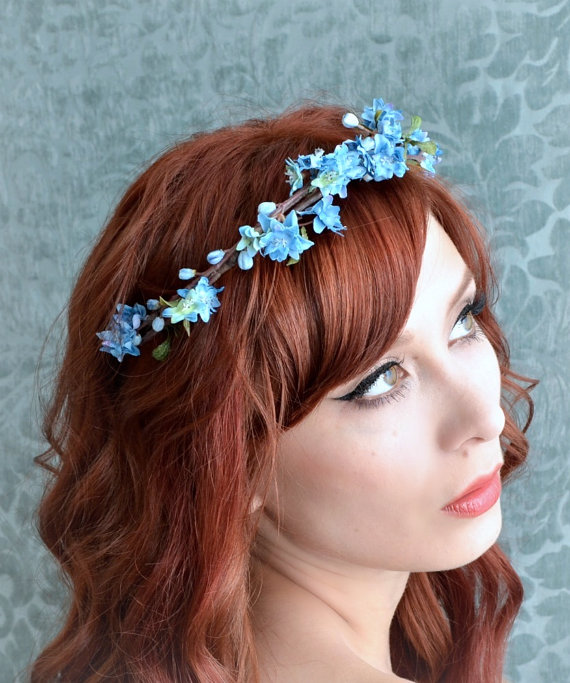 a young woman with curly red hair and blue flowers in her hair