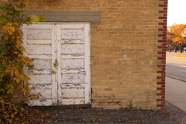 an abandoned door is next to the brick building