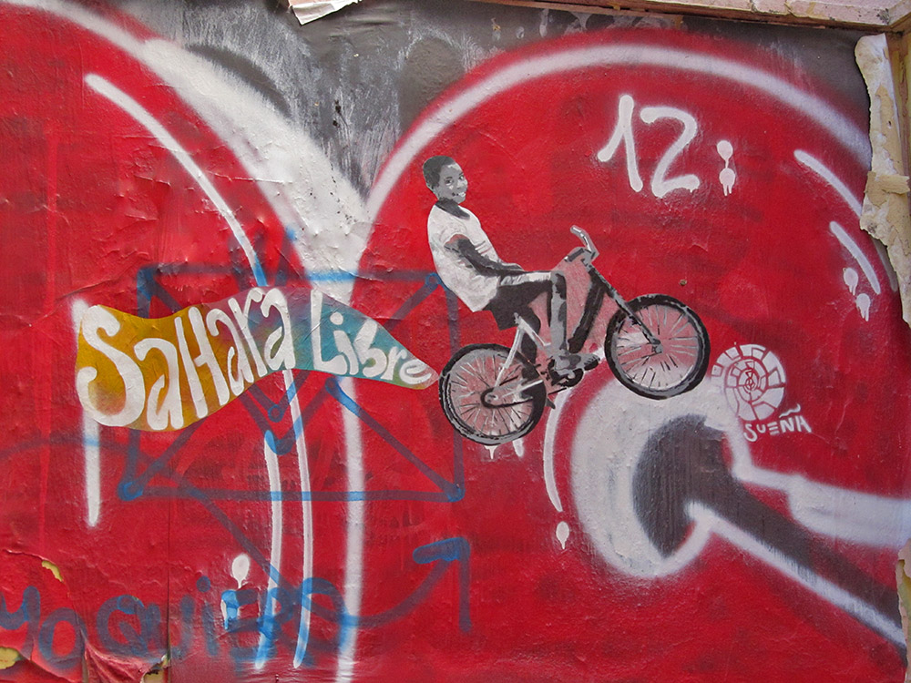 a graffiti covered wall has a bicycle on it