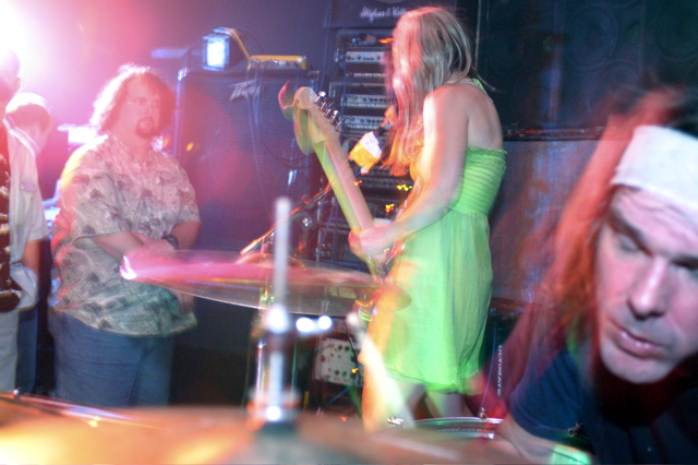 a woman in a neon green dress playing drums with others