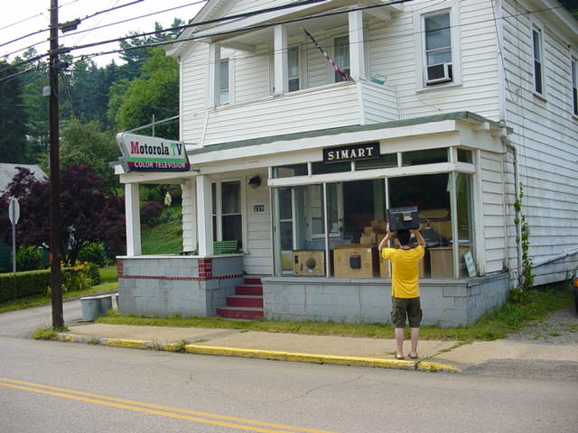 man in yellow shirt with hands up next to store