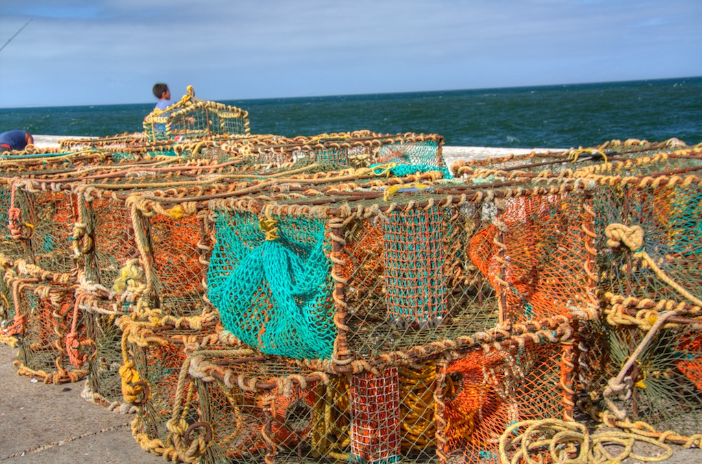some fishing nets with one being pulled up to the beach