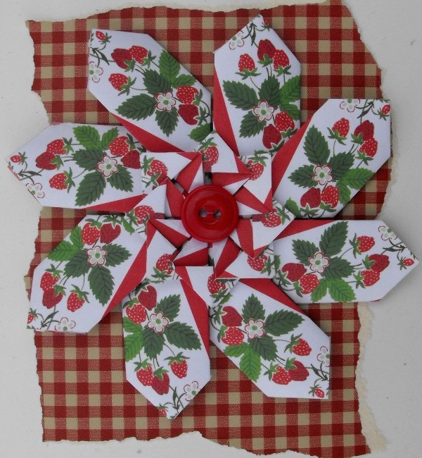 a paper rose made to look like strawberries on a checkered background