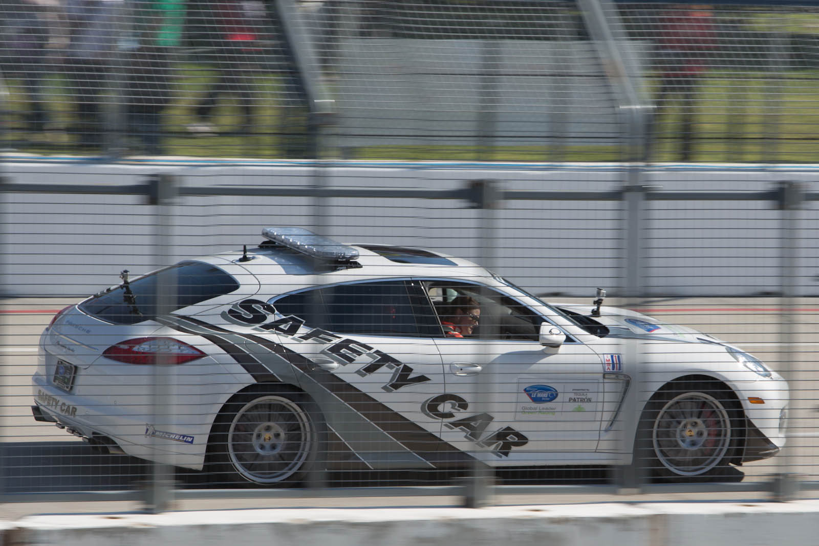 a race car driving past a crowd in a fence