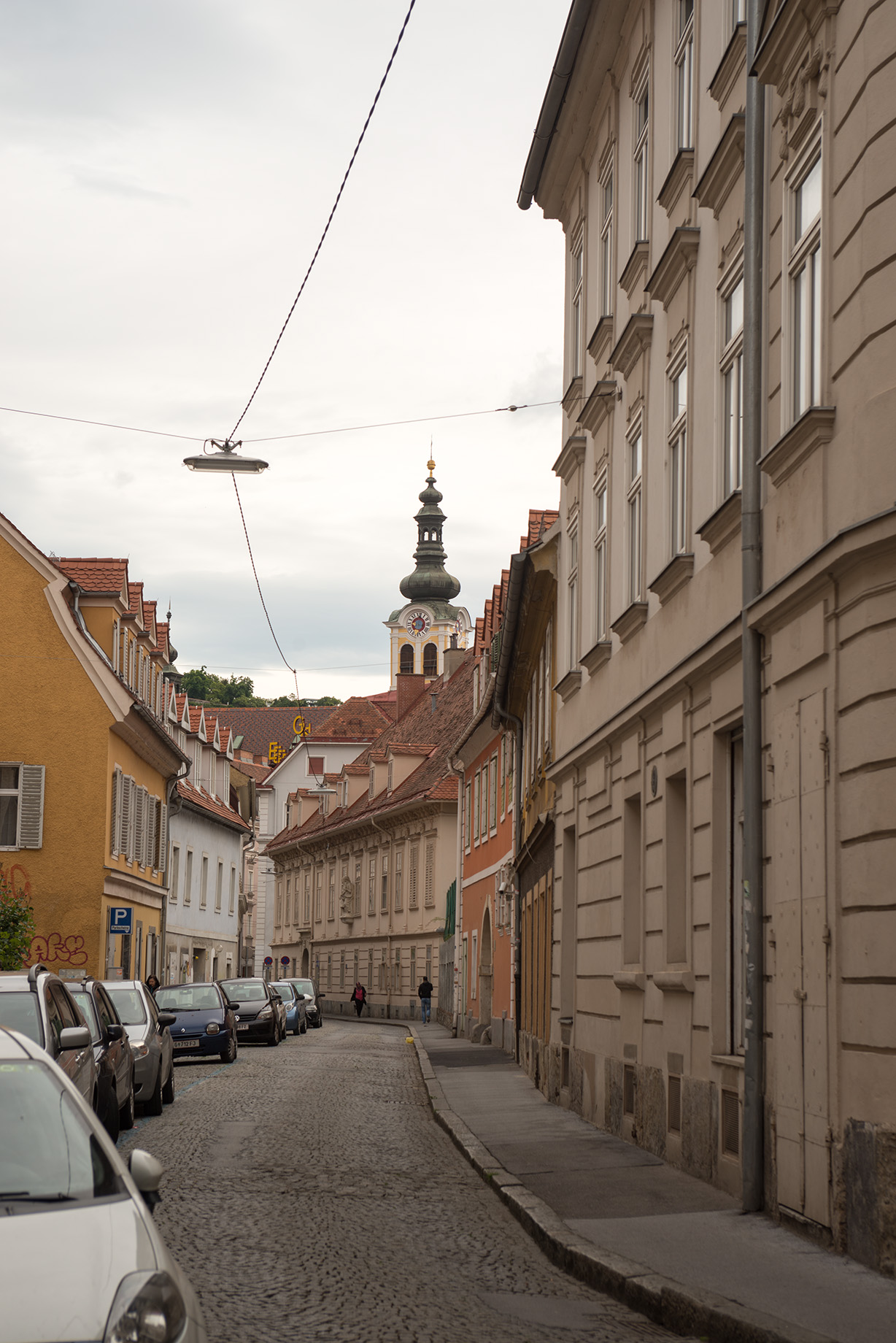 a cobblestone street with cars parked on both sides