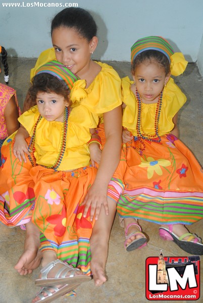 a bunch of small girls in dresses are sitting on the floor