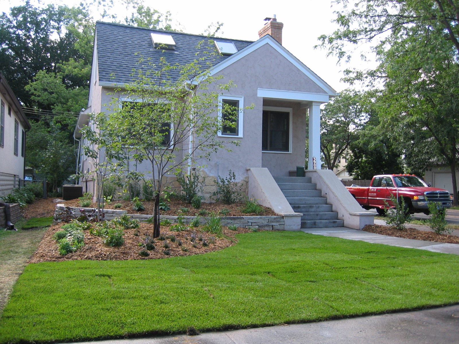 a small house with a grass yard and driveway