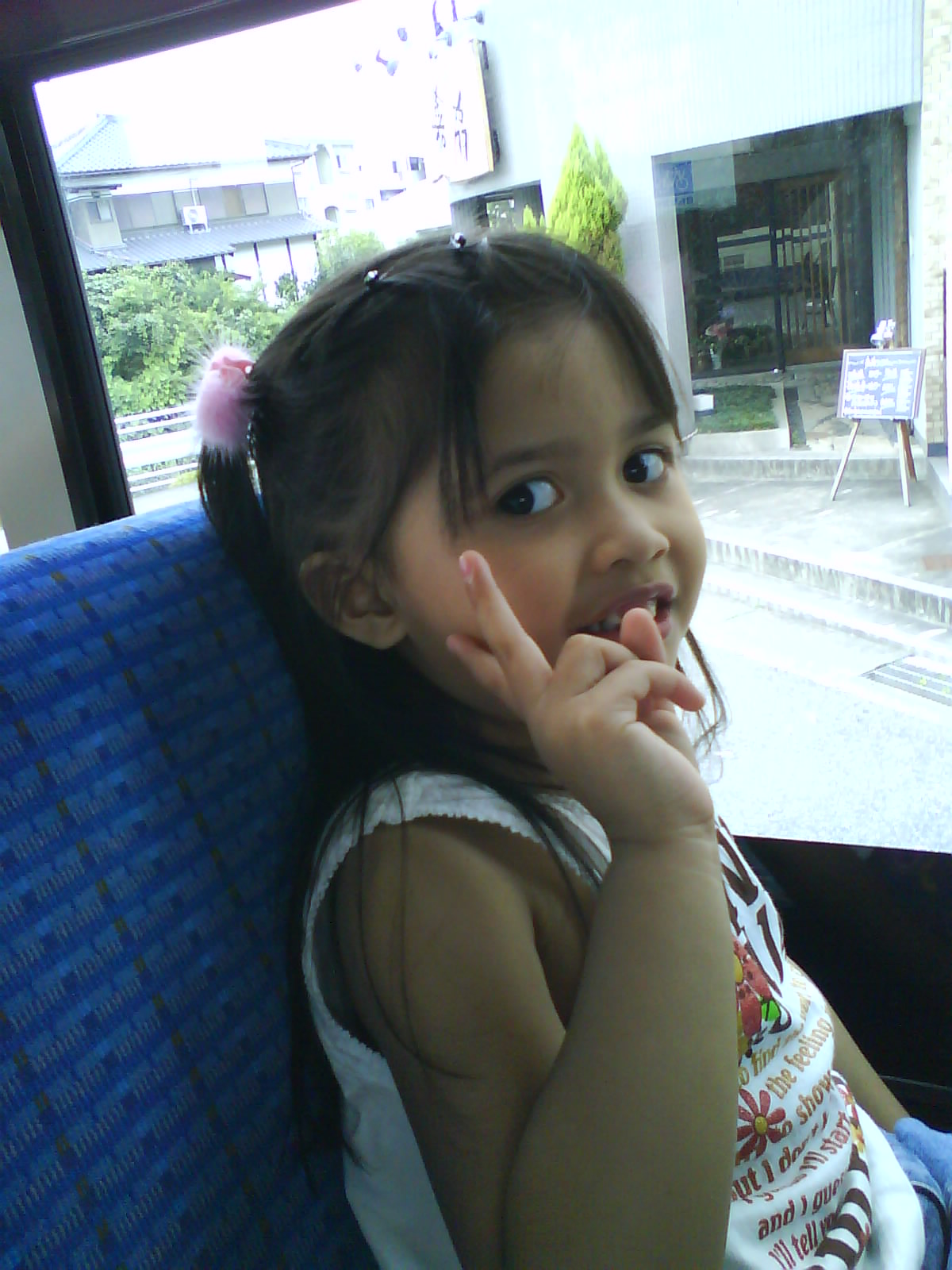 a little girl sitting in the back of a bus