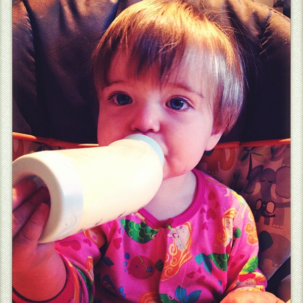 a baby drinking milk out of a bottle