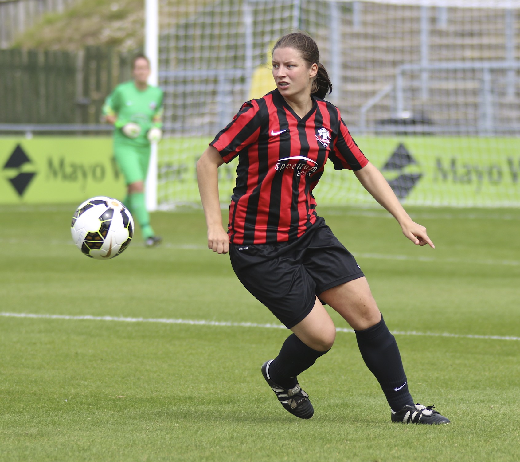 a girl playing soccer on the field wearing a jersey