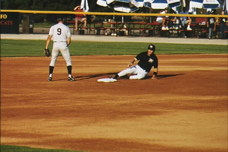 a man on the base is waiting to tag a runner