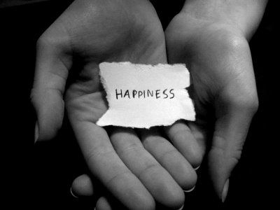 a woman is holding her hands in one of the palms with a piece of paper with the word happiness on it