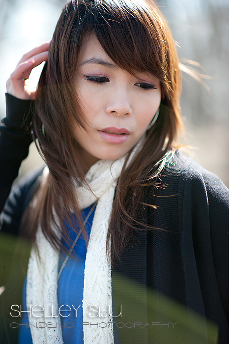 a woman with long brown hair wearing a scarf and a black cardigan