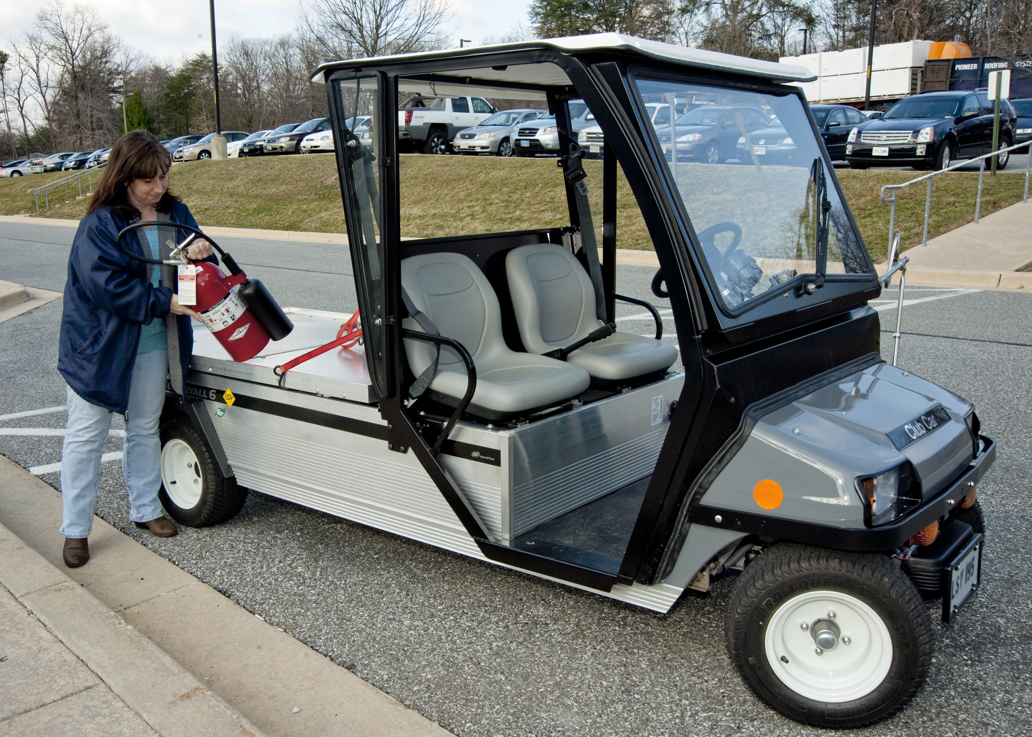 a woman in a blue jacket holding a red and white golf cart