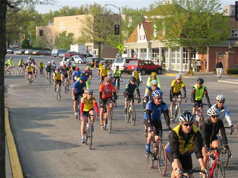 a long group of people riding bicycles down a street