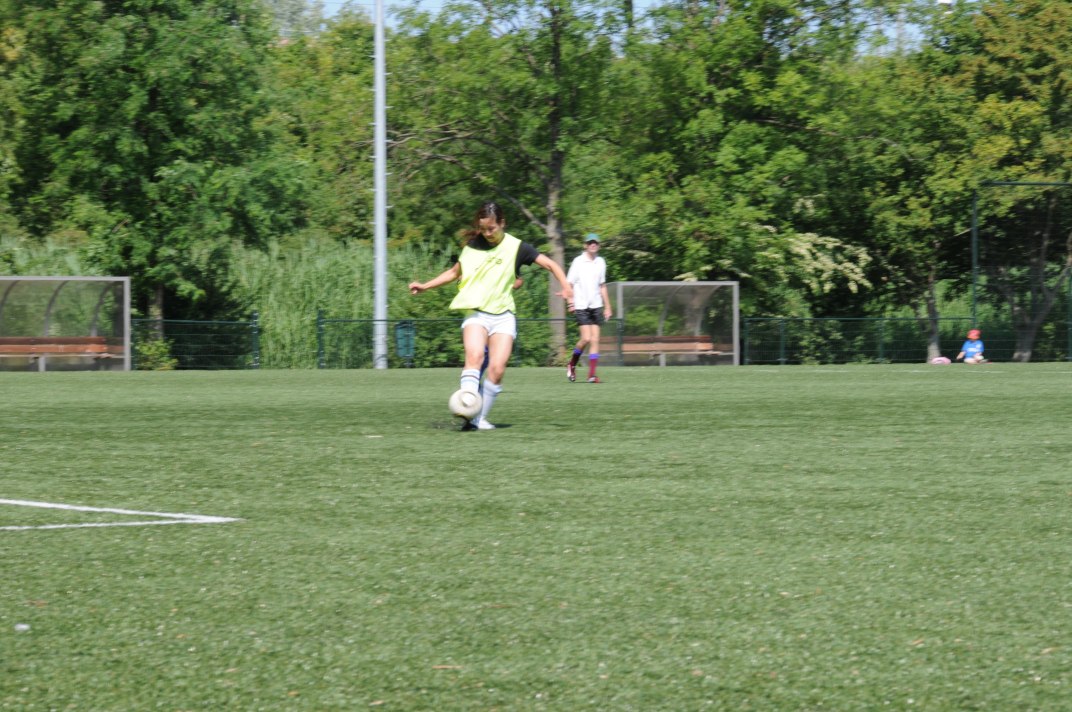 a girl soccer player kicking a ball towards the goal