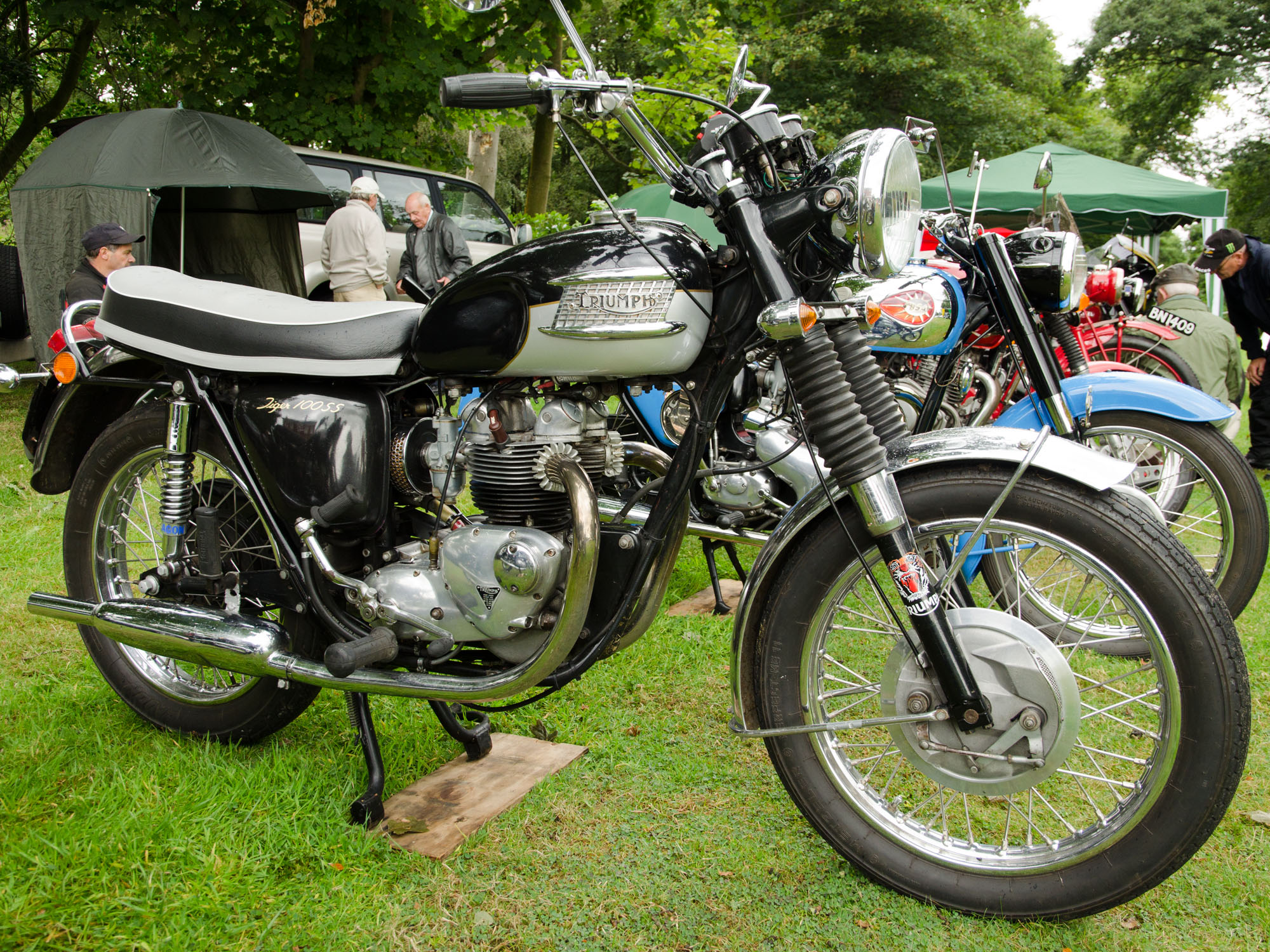 several motorcycles parked in a grassy area with tents in the background