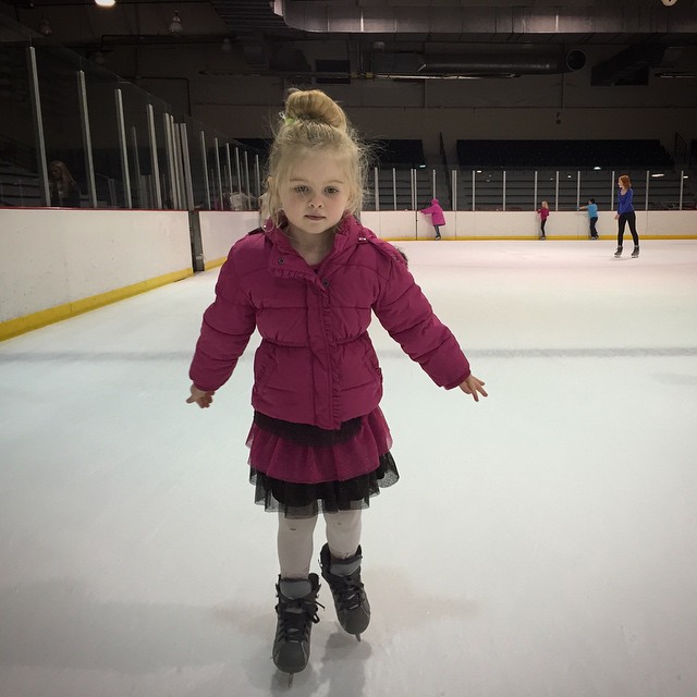 a little girl on a skating rink wearing ice boots