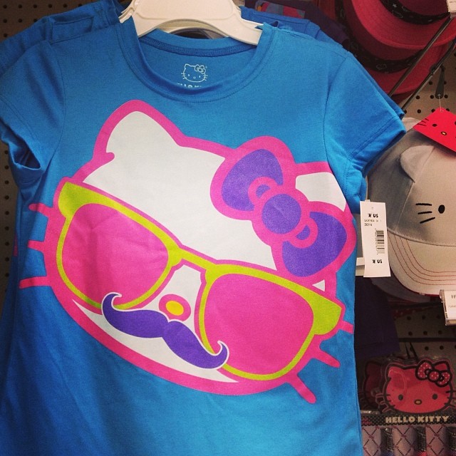 a hello kitty t - shirt hanging on a wall in a store