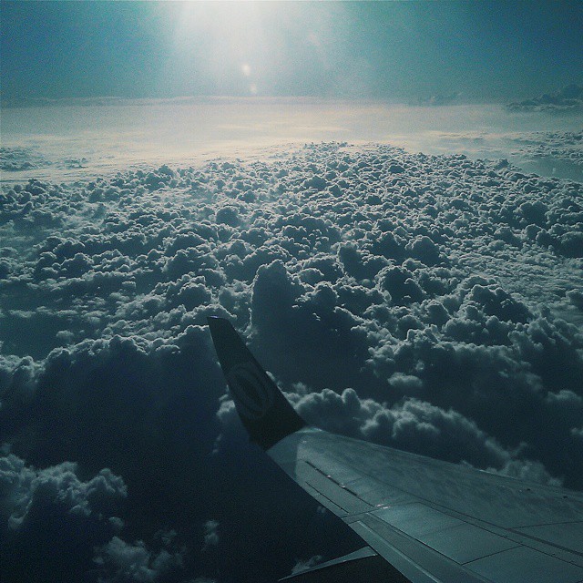 the view from an airplane window of clouds and a sun