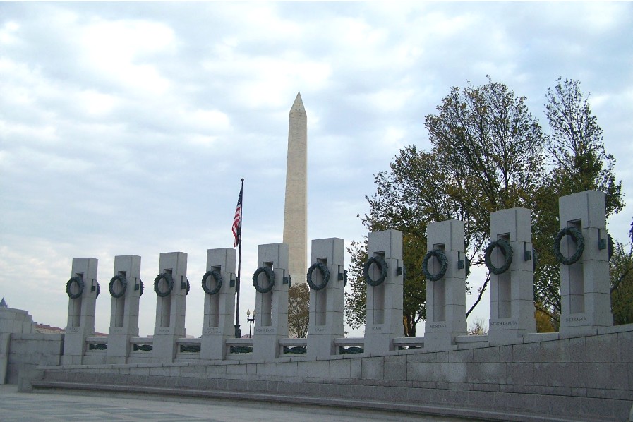 the monument is made of stone and features sculptures of wreaths and flags