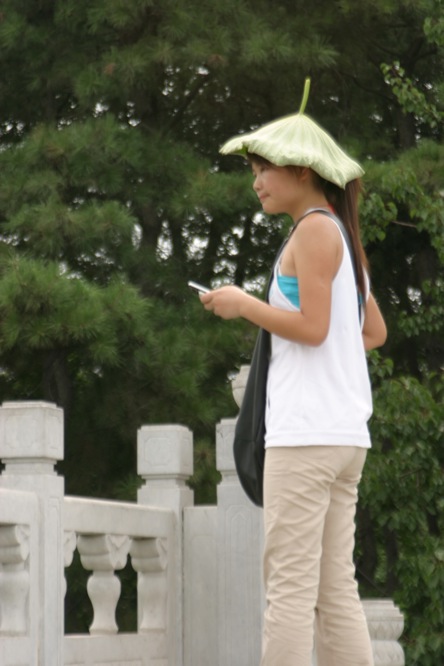 a woman with a green fruit hat standing with a cell phone