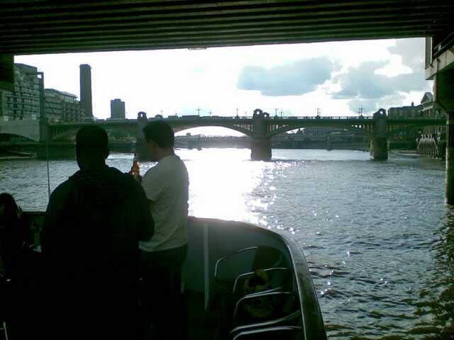 two people sit on the boat in front of an arched bridge