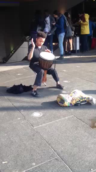 a boy playing a beat drums while on a city street