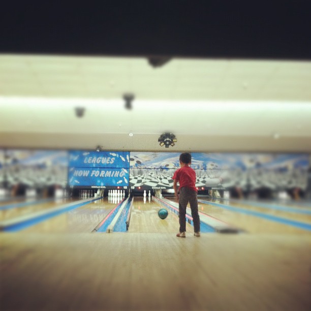 a man standing on a bowling alley with his foot in the ball