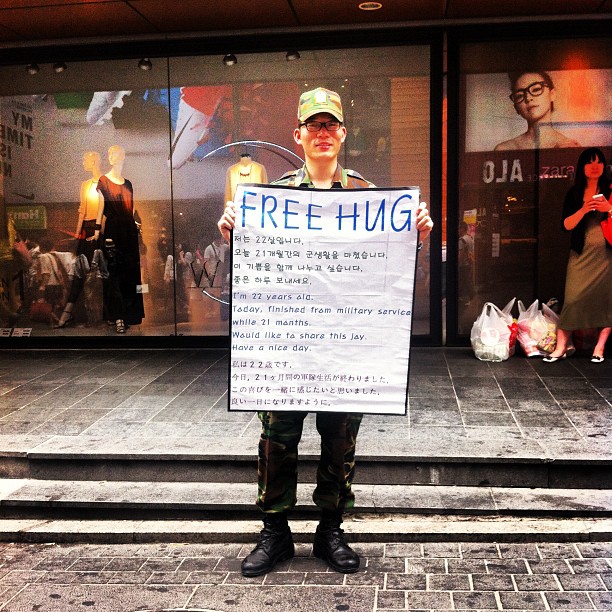 a man holding a free hug sign in front of a store
