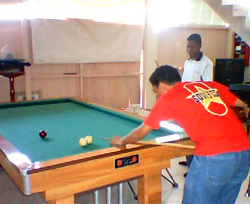 two men playing pool inside of a building