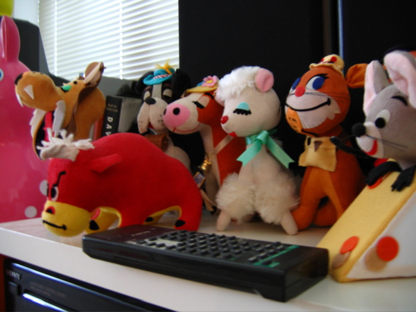 toys are lined up along a desk in front of a window