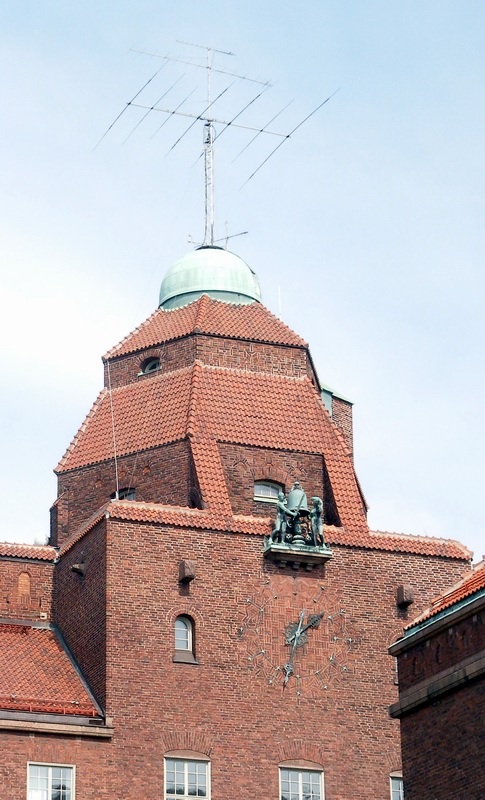 large brick building with small metal sculpture on the top