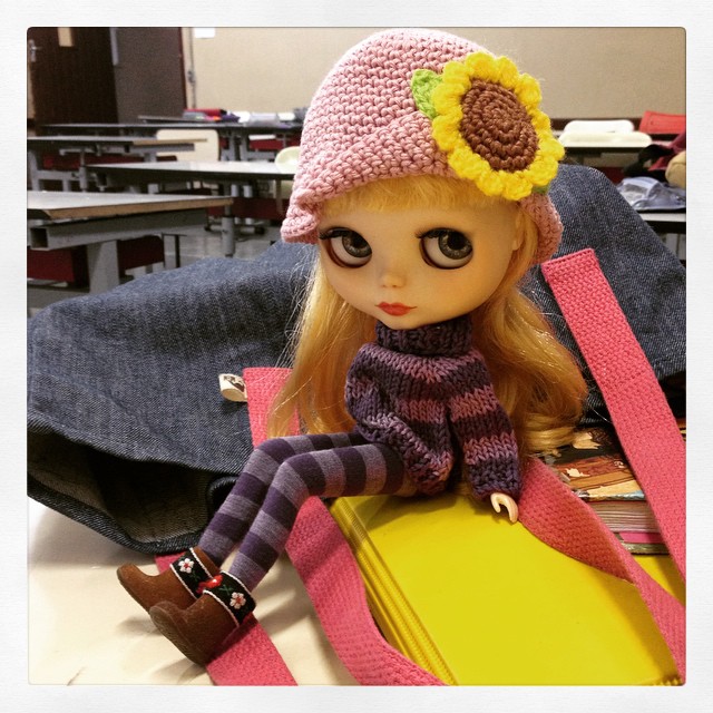 doll sitting on top of a yellow suitcase