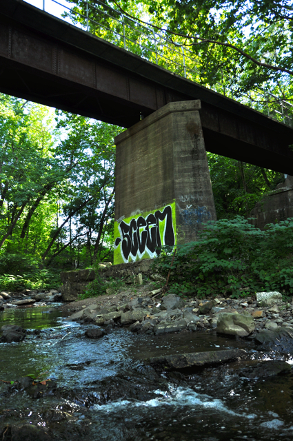 a graffiti covered bridge spanning over a stream