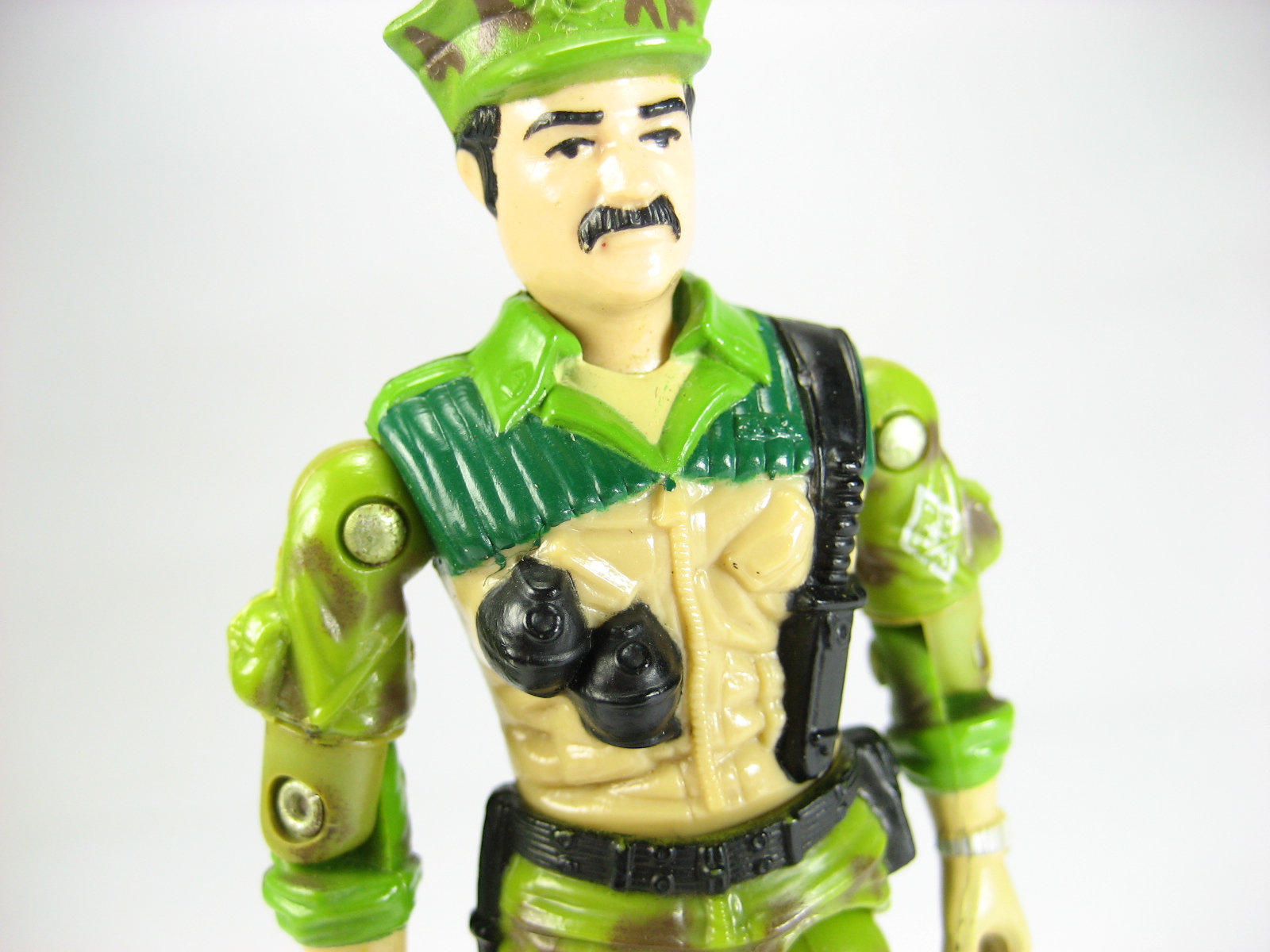 a toy figure is posed in green and tan