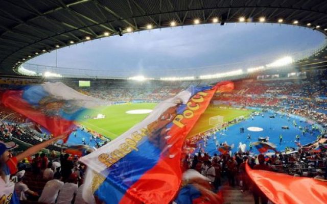 two fans waving a russian flag in front of the stadium
