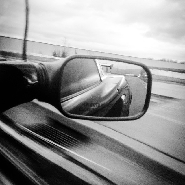 a rear view mirror on the side of a car driving on a highway