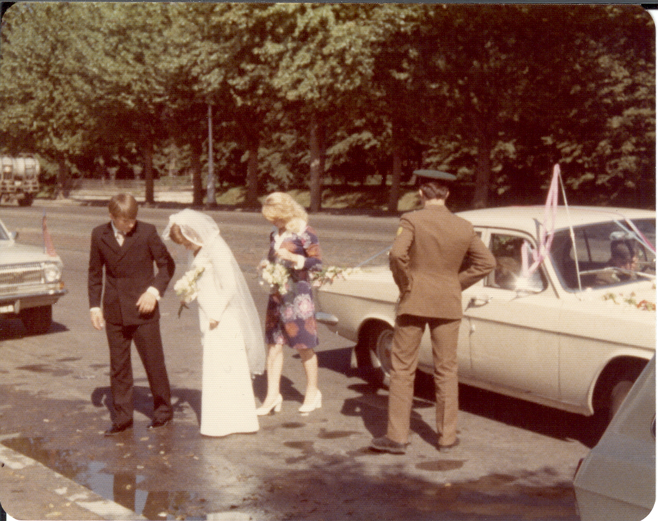 people stand in front of old cars on a street