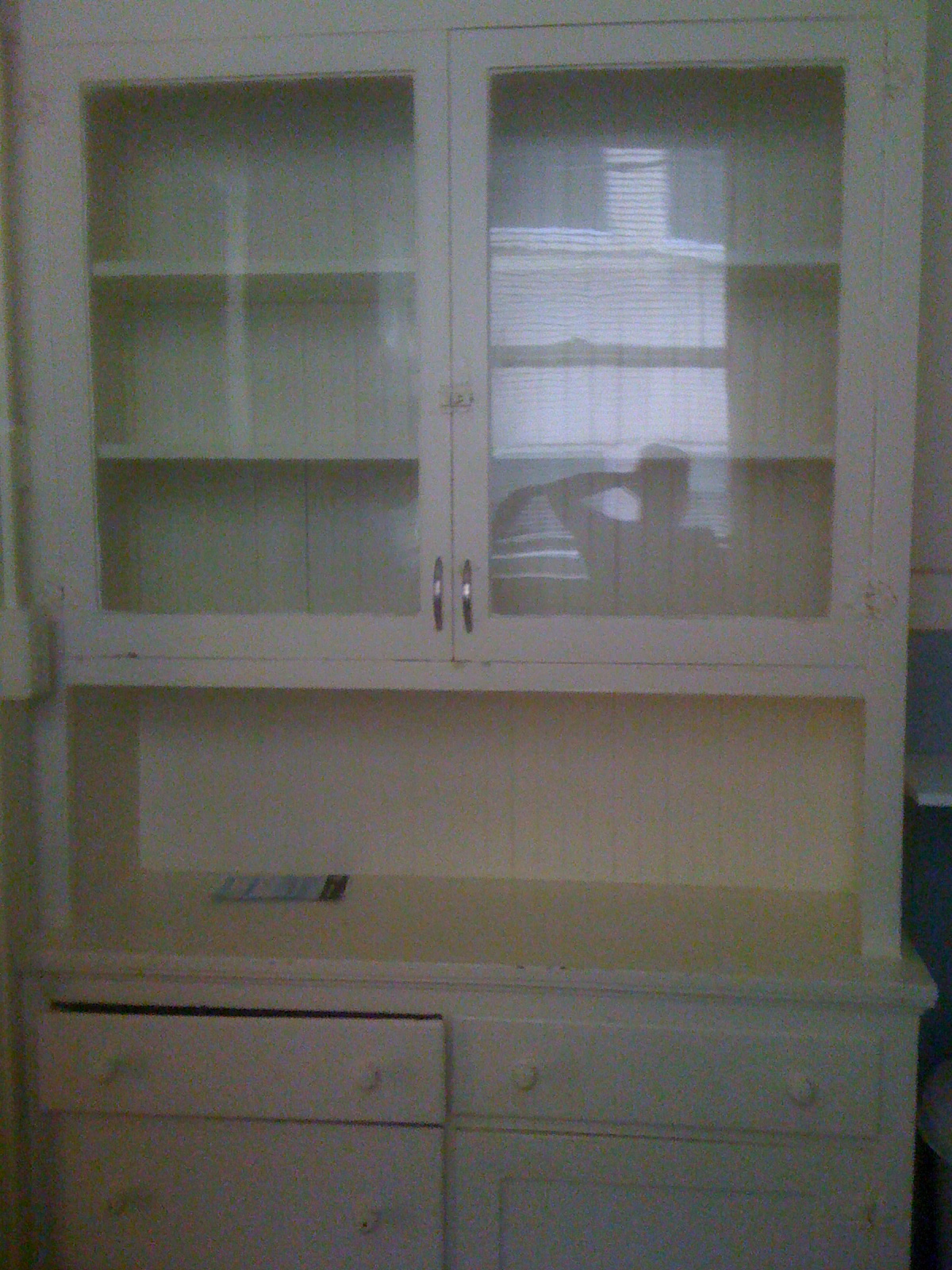 an empty white cabinet with glass doors and drawers