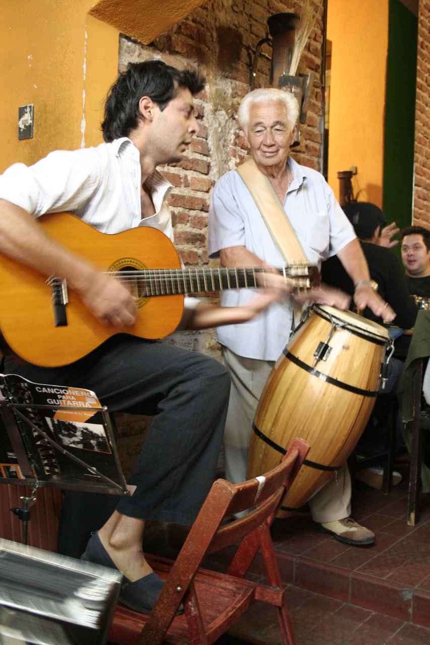 two men sitting next to each other holding guitars