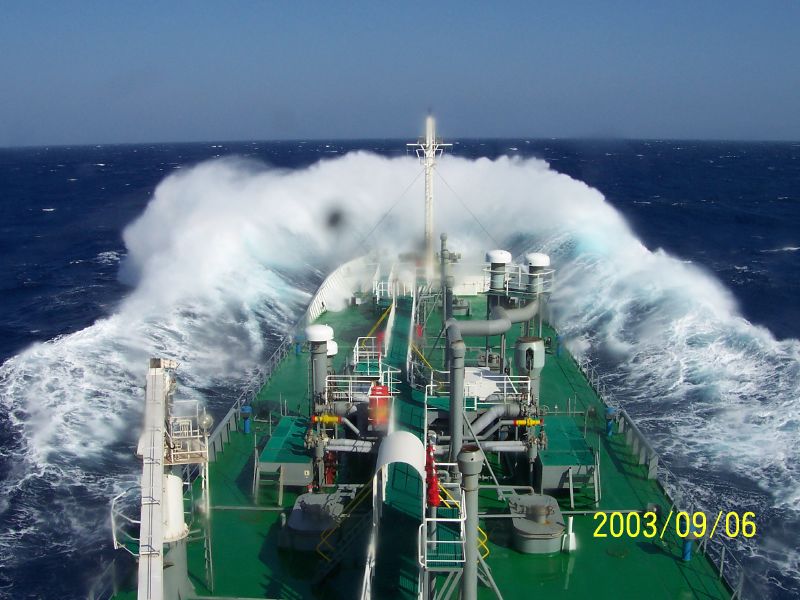 the top of a ship with the ocean spray in the background